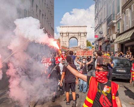 A crowd of protesters, the one nearest the camera holding up a flare, near the Port d’Aix, in Marseille