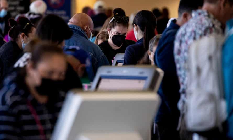 Travelers, mostly masked, use kiosks at the Los Angeles international airport.