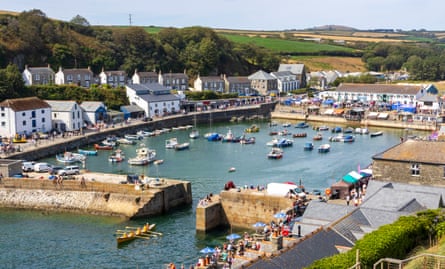 A honey square stone harbour, lined with historic houses and cottages and with many small boats and craft inside.