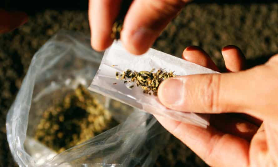 An addict rolls a joint using a synthetic cannabinoid