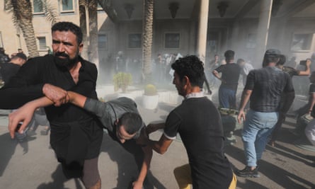 Supporters of Iraqi Shiite cleric Moqtada al-Sadr help injured protesters during clashes with anti-riot forces in Baghdad.