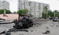 The charred remains of a car in front of a bomb-damaged apartment block