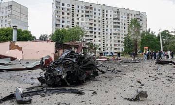 The charred remains of a car in front of a bomb-damaged apartment block