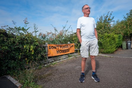 Richard Croucher stands beside a ‘Don’t flood our homes’ sign.