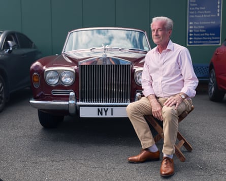 Nicholas Young sitting in front of his burgundy Rolls-Royce with the number plate “NY I”