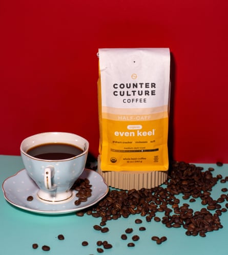 a package of counter culture even keel coffee next to a cup of coffee and surrounded by coffee beans