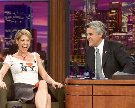 Jenna Elfman sitting on a couch with Jay Leno behind a desk beside her