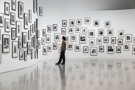 A man takes in numerous black and white photographs as they’re displayed on a curving wall
