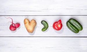 Set of five ugly vegetables: potato, tomato, cucumber and radish laid out in row on white wooden background