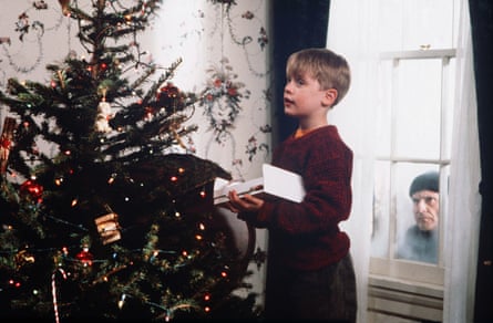 Culkin looking at a Christmas tree as Pesci peers in at him through the window