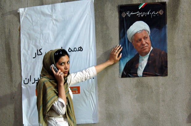 A young woman chats on her mobile phone next to a campaign poster of Ali Akbar Hashemi Rafsanjani at a rally in northern Tehran in 2005.
