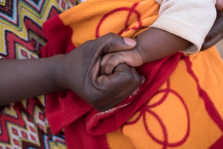 Merkam Linou, from Cameroon, clasps her baby’s hand while telling of an ordeal in the desert
