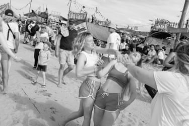 black and white image of two teenage girls mucking about on a Dutch seaside boardwalk among crowds of other tourists