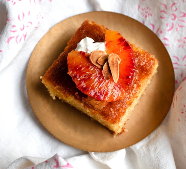 A square of cake, topped with blood orange slices, cream and toasted almond flakes