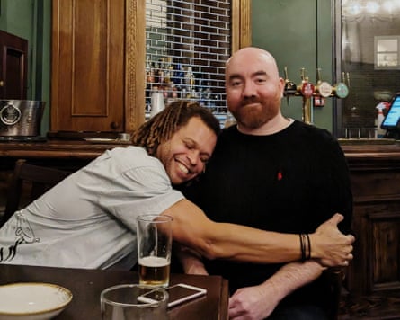 Two men in a pub, one hugs the other