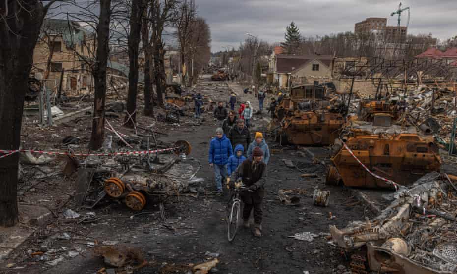 Residents walk past destroyed Russian military machinery on the street, in Bucha, the town which was retaken by the Ukrainian army, northwest of Kyiv, Ukraine.