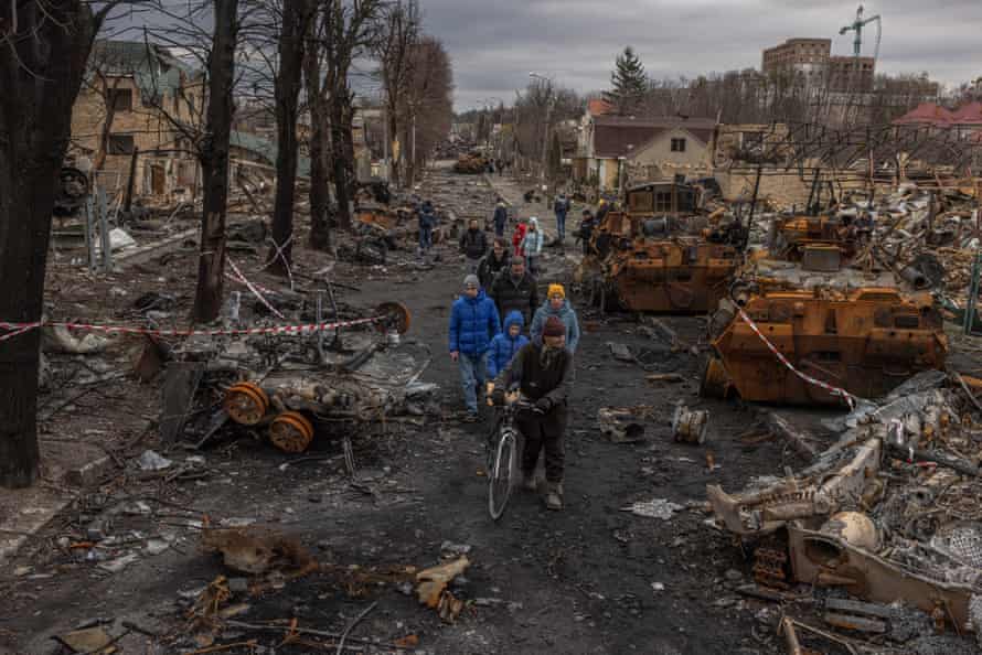 Residents walk past destroyed Russian military machinery