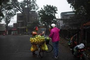 A vegetable seller speaks to a customer during her early morning rounds in Hanoi, Vietnam
