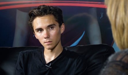 a teenage boy wearing black T-shirt looks at a woman