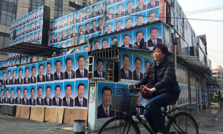 A woman cycles past a building covered in portraits of Chinese president Xi Jinping in Shanghai. 