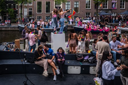 Lots of people in colourful outfits on boats on the canal