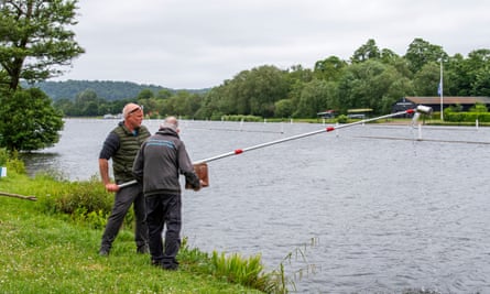 Dave Wallace using a long poll with a can-like collecting device on the end to test river for E coli