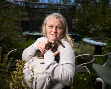 A woman cuddling two rare ducks against her chest
