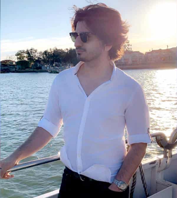 Mustafa stands on a boat at sunset.