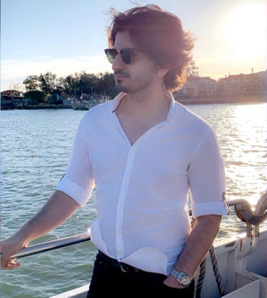 Mustafa stands on a boat at sunset.
