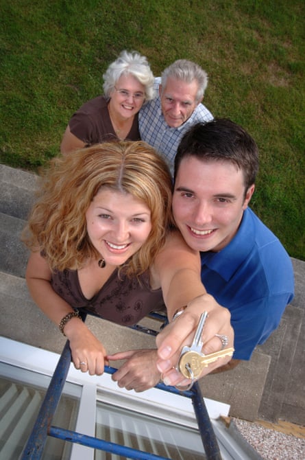 A couple atop a ladder show their keys to their new home with their silver-haired parents pictured below
