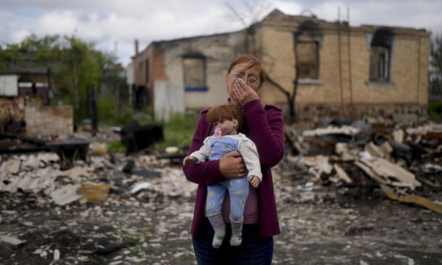 Nila Zelinska memegang boneka milik cucunya di depan rumahnya yang hancur di Potashnya, di luar Kyiv, Ukraina, pada bulan Mei.