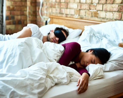 A couple sleeping in bed with eyemasks on