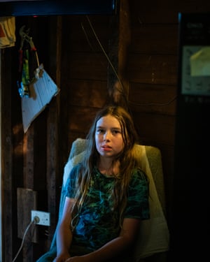 A young girl sitting in a chair in the middle of a dark room.