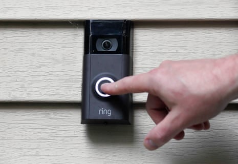 A hand pushes the button on a Ring doorbell.
