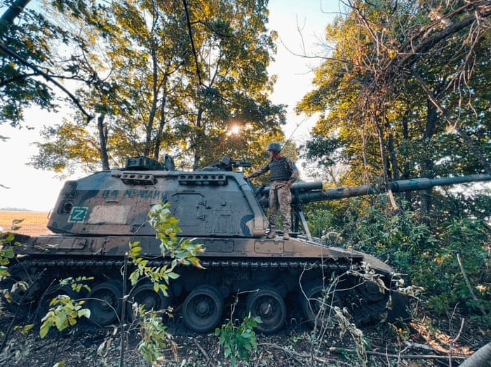 Soldier stands on a tank-like vehicle in a forest