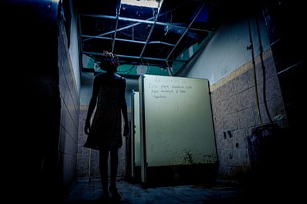 Sally, 32, stands in one of the two shelter bathrooms shared by 40 residents