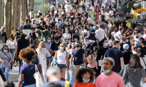 People wearing face masks walk on the Champs Elysees in Paris.