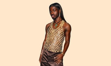 Lil Nas X wearing a vest made of gold disks, and brown shiny trousers
