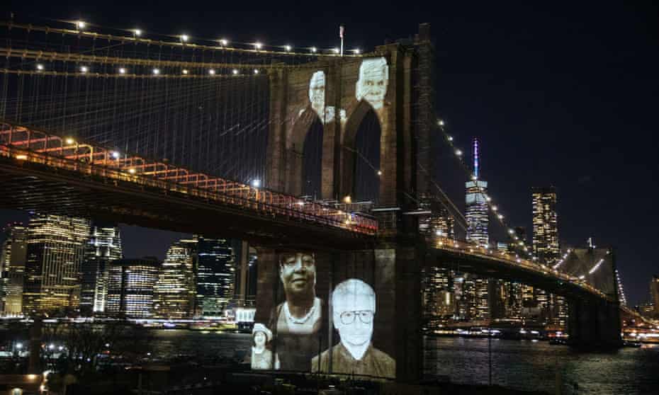 The faces of Brooklyn residents who died from Covid are remembered with photographs projected on to Brooklyn Bridge, New York on 14 March.