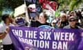 People hold a banner that reads "End the six week abortion ban"