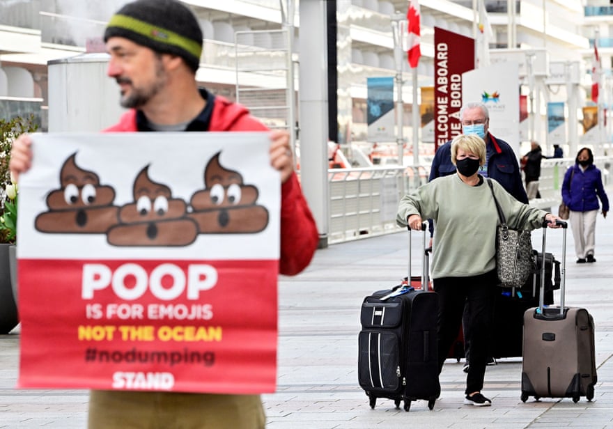Man stands in front of cruise ship holding sign that reads ‘Poop is for emojis, not the oceans’. Passengers with luggage can be seen behind him.