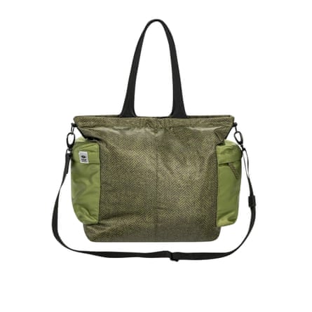 A herringbone tote bag with green nylon side pockets and black handles