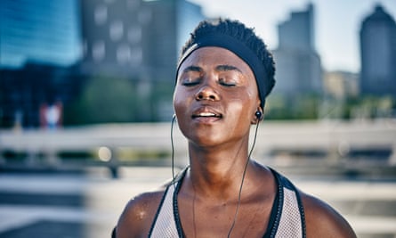 Woman in running gear with eyes closed and earphones in