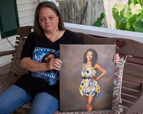woman sits on porch outside home holding canvas photo of young woman in dress smiling