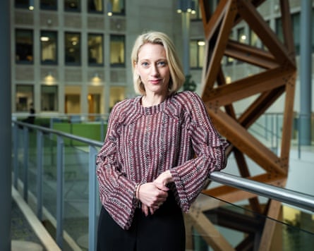 Waxman in red blouse posing in modern building