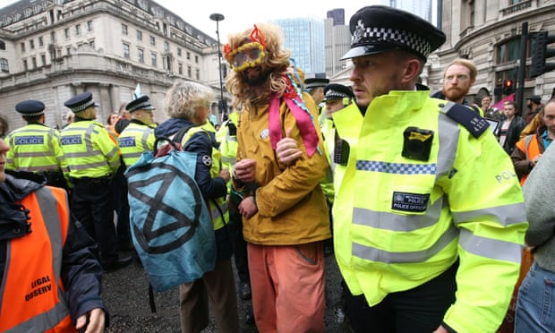 A protester is led away by police as others block the road outside Mansion House in the City of London.