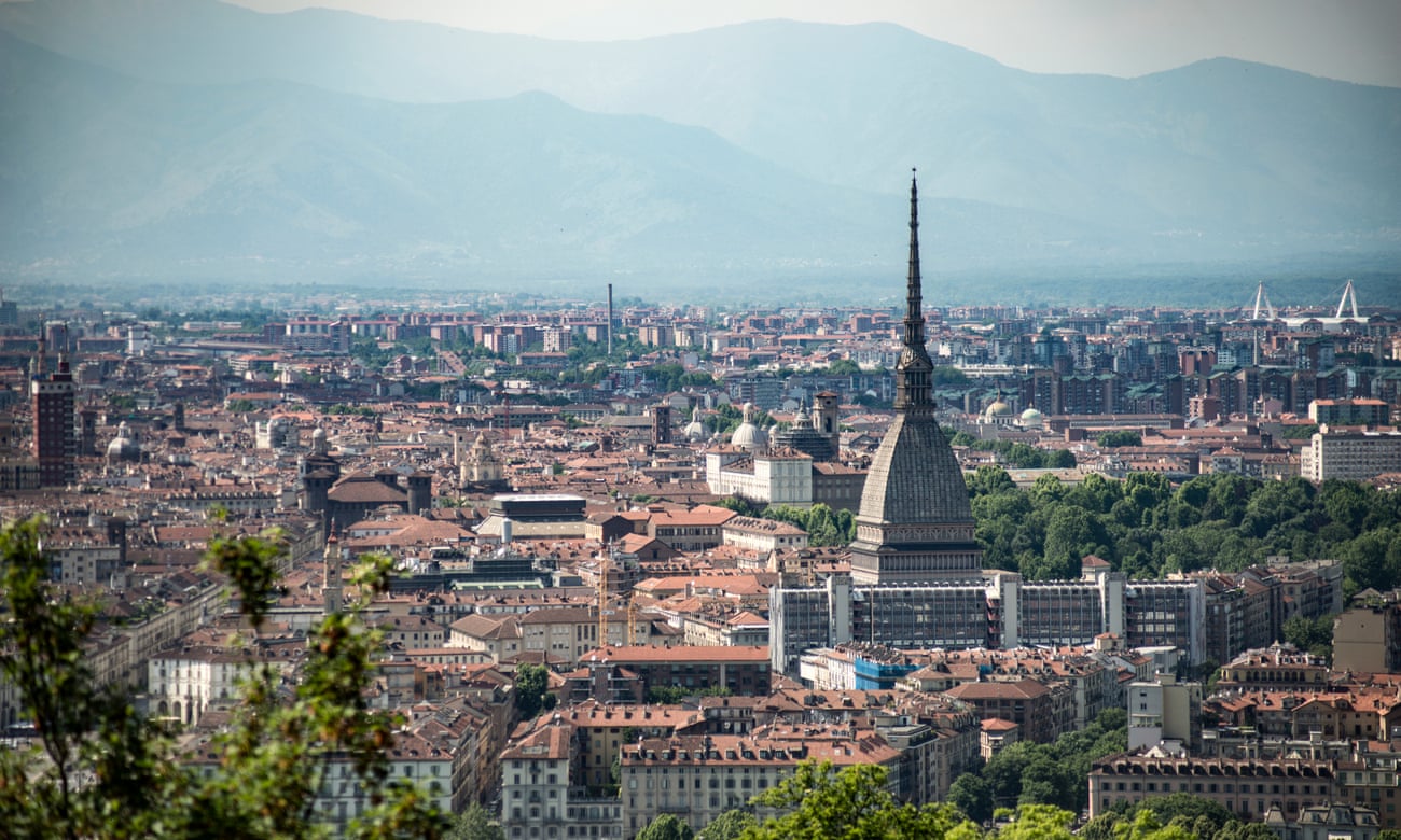 This cityscape of Turin takes in the Mole Antonelliana with its huge spire, surrounding buildings and mountains in the distance.