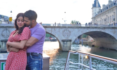 Janhvi Kapoor and Varun Dhawan embrace on a boat on a river with a bridge behind them.