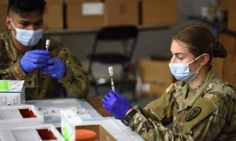 Army medics fill syringes with Johnson &amp; Johnson Covid-19 vaccine at a vaccination site in Florida