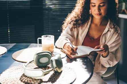 A woman writes in her notebook at a table